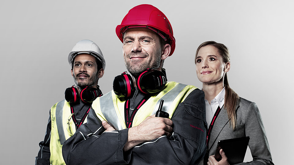 One worker stands in the front crossarmed, one woman in office clothing and another worker are standing behind