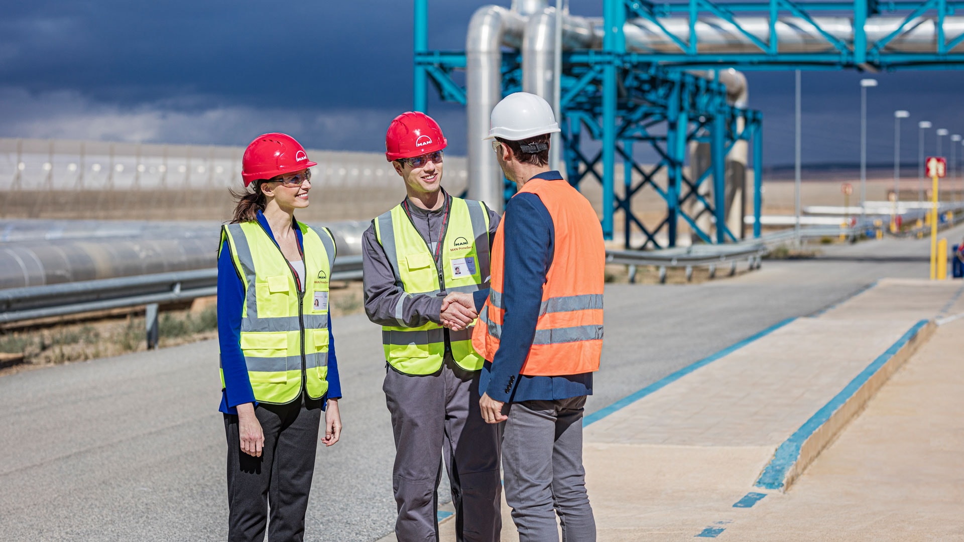 three workers talking to each other outside the refinery